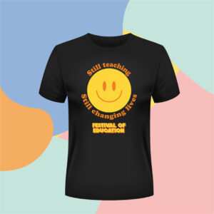 Black T-shirt with a large yellow smiley face and orange curved text around it reading 'Still teaching' and 'changing lives'; below is bold yellow text 'Festival of Education' on the shirt. The colorful abstract background is visible behind.